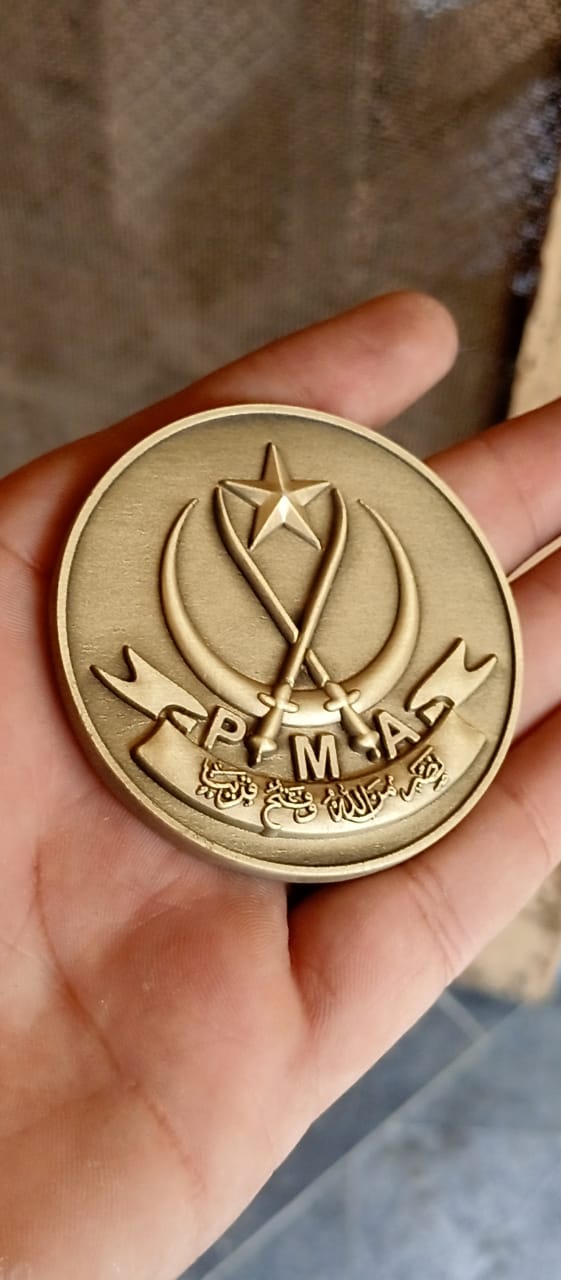 A finely crafted brass-finished medallion featuring the prestigious PMA emblem and crossed sabers, symbolizing honor and military excellence